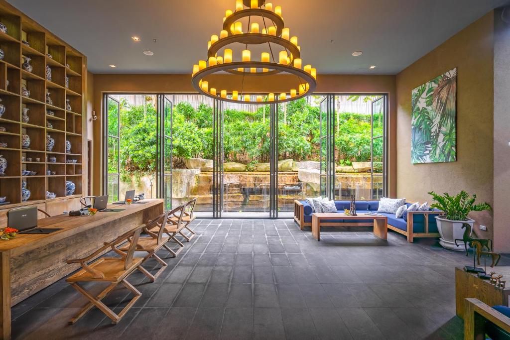 a large lobby with a large window and a chandelier at Sunsuri Phuket - SHA Plus in Nai Harn Beach