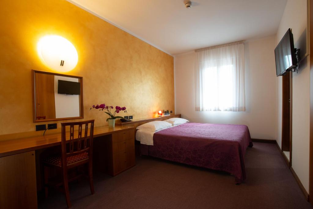 a hotel room with a bed and a desk and a television at Hotel Cima in Conegliano