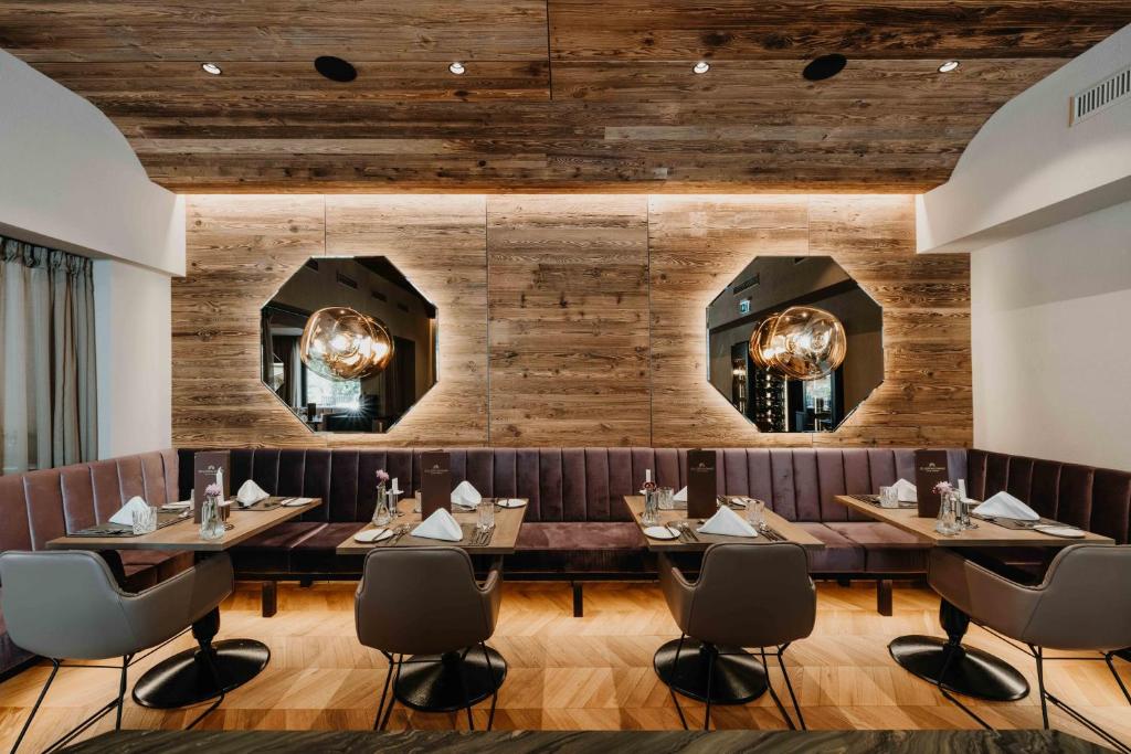マイヤーホーフェンにあるAlpine Hideaway ZILLERTALERHOF - 4 Sterne Superiorの木製の壁とテーブルと椅子が備わるレストラン
