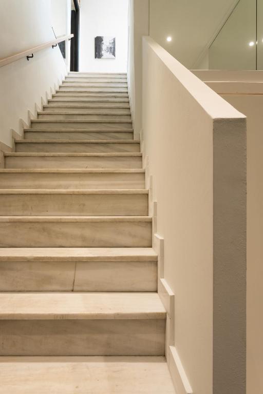 a staircase in a house with white walls and concrete stairs at SYROS SOUL LUXURY SUITES in Ermoupoli