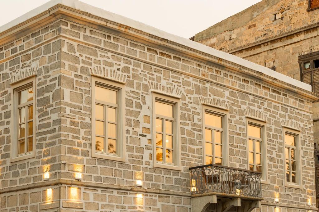 a stone building with windows and a balcony at SYROS SOUL LUXURY SUITES in Ermoupoli