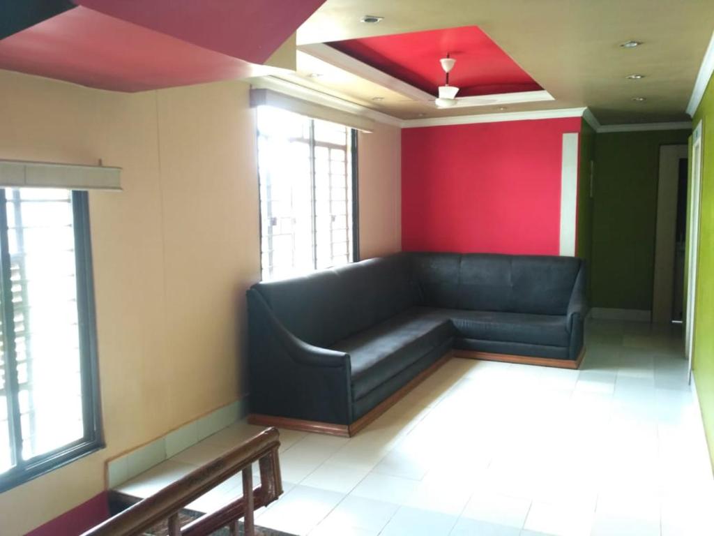 a waiting room with a black leather couch and red wall at Omran by WB Inn in Rānchī