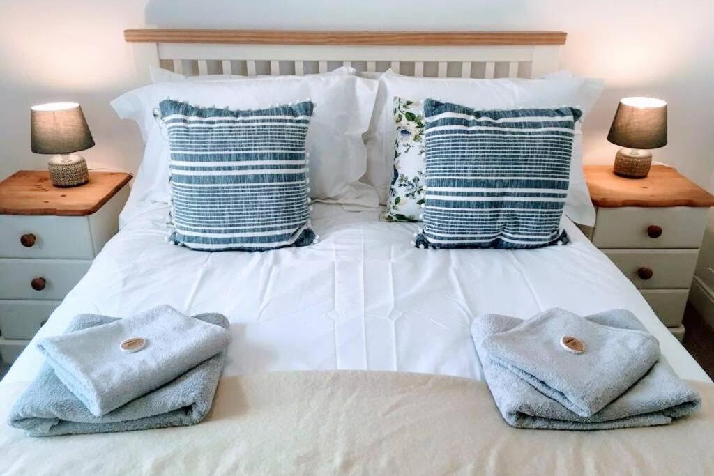 uma cama branca com toalhas e almofadas em Former Quarryman’s 3-bed house 5 min to Zip World em Bethesda