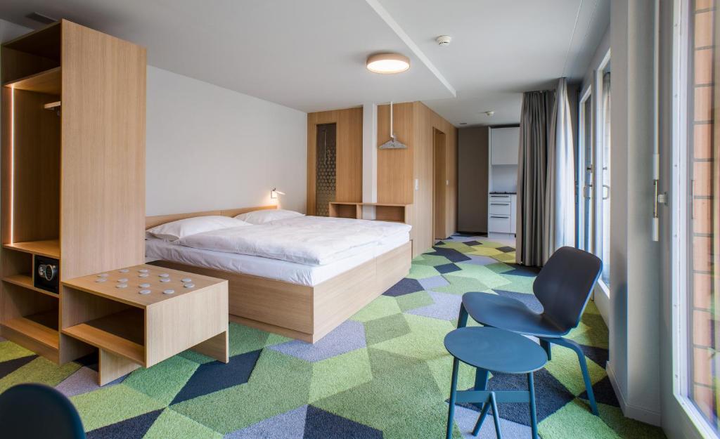 um quarto com uma cama, uma secretária e cadeiras em The Lab Hotel & Apartments em Thun