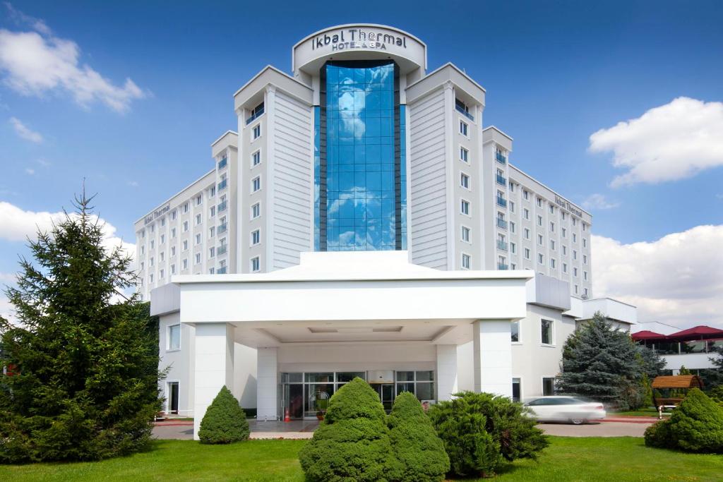 a large white building with a clock tower on it at Ikbal Thermal Hotel & Spa Afyon in Afyon