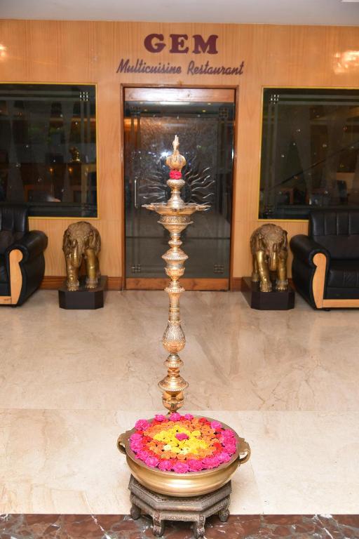 einen Brunnen in der Mitte eines Gebäudes mit Blumenarrangements in der Unterkunft Hotel Sonas in Tiruchchirāppalli