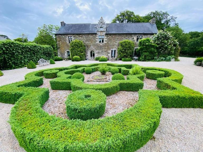 un giardino di fronte a una casa con una siepe di Manoir de Kerledan a Carhaix-Plouguer