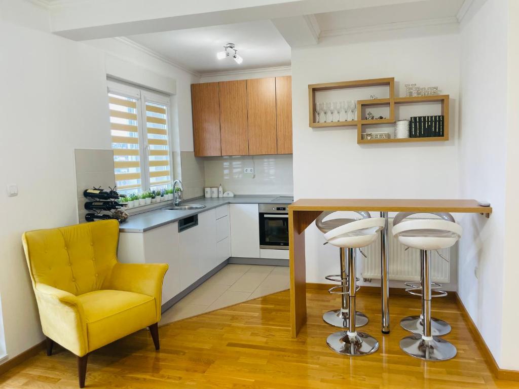 a kitchen with a yellow chair and a table at Apartman M&M in Doboj