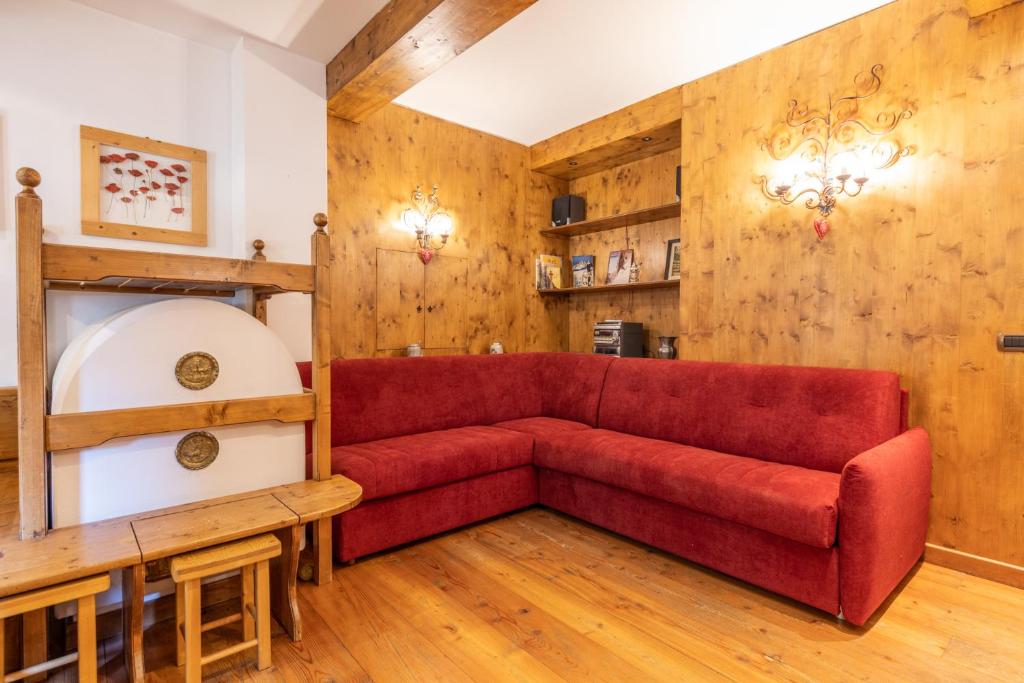 - un canapé rouge dans une chambre dotée de murs en bois dans l'établissement Casa Cristallo, à Cortina dʼAmpezzo