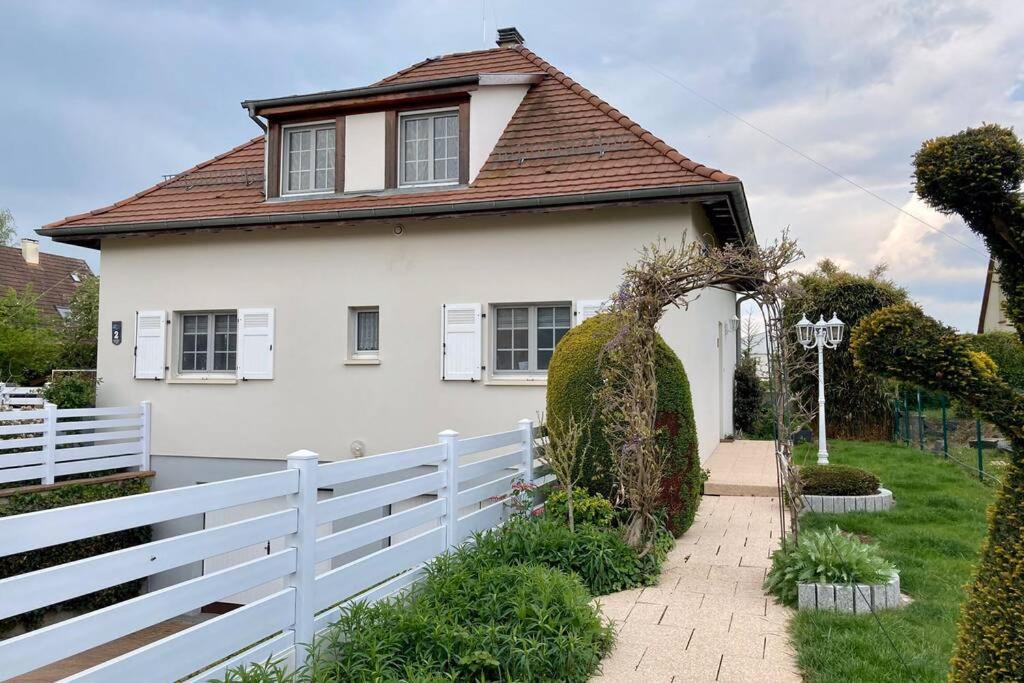 Uma casa branca com uma cerca branca à frente. em Le papillon,Logement cosy en Alsace em Erstein