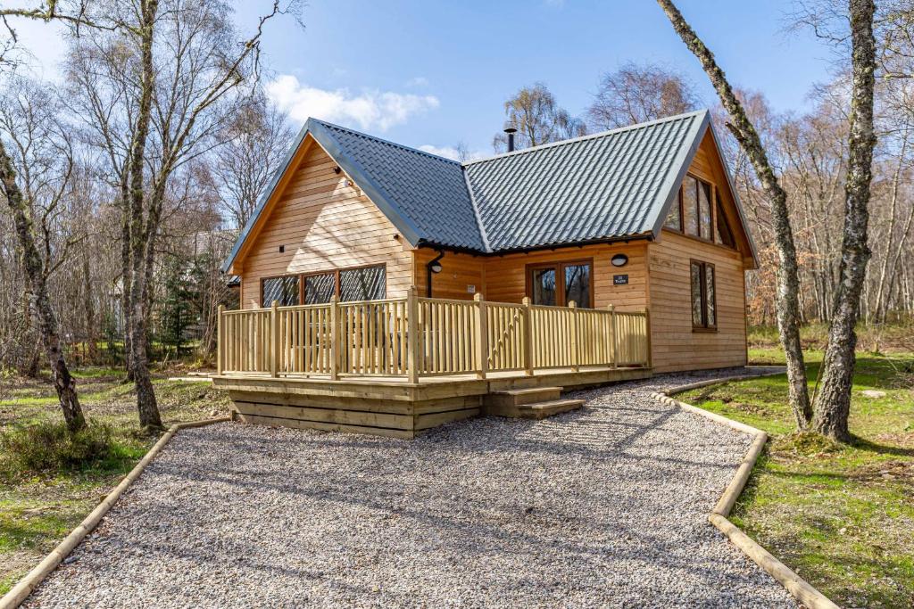 a log cabin with a porch and a deck at Thistle Lodge 22 with Hot Tub in Belladrum