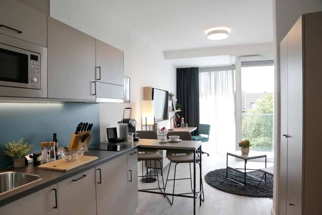 a kitchen with white cabinets and a table with chairs at PM-AM Apartments GmbH in Dortmund