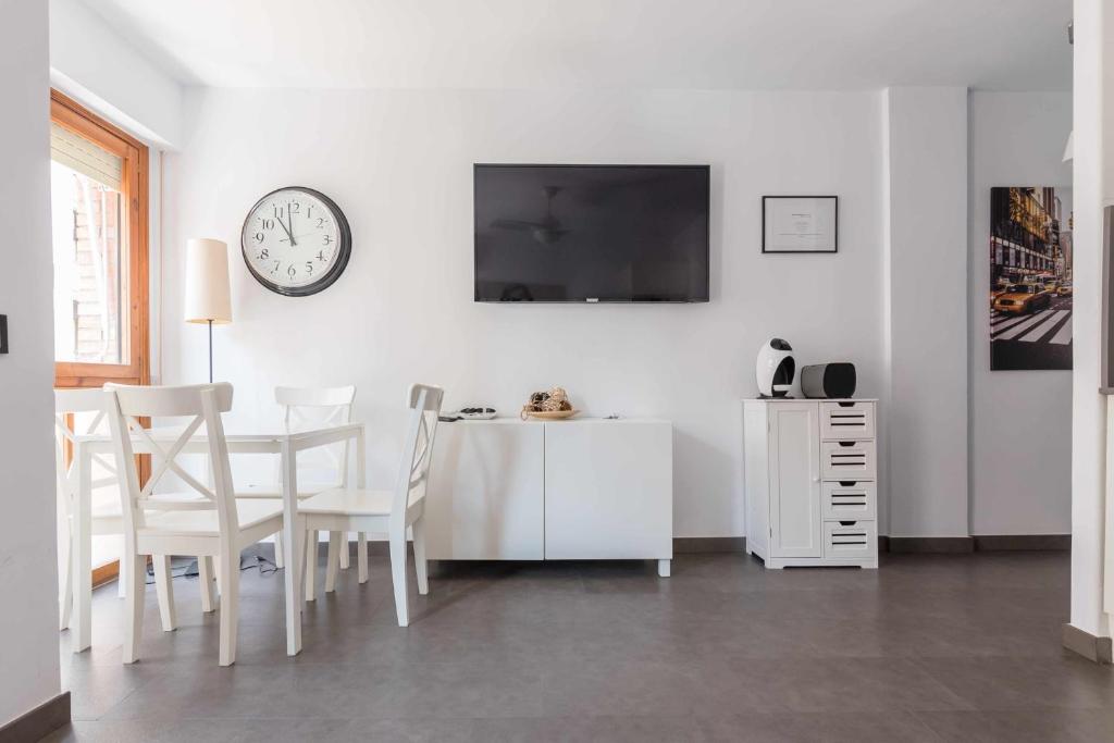 a white dining room with a table and a clock on the wall at Apartamento FLORIDABLANCA in Murcia