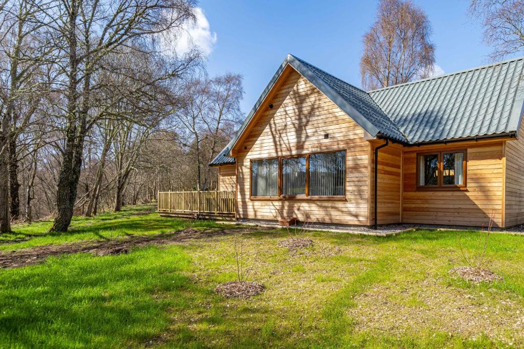 uma pequena casa de madeira com um quintal em Thistle Lodge 18 with Hot Tub em Belladrum