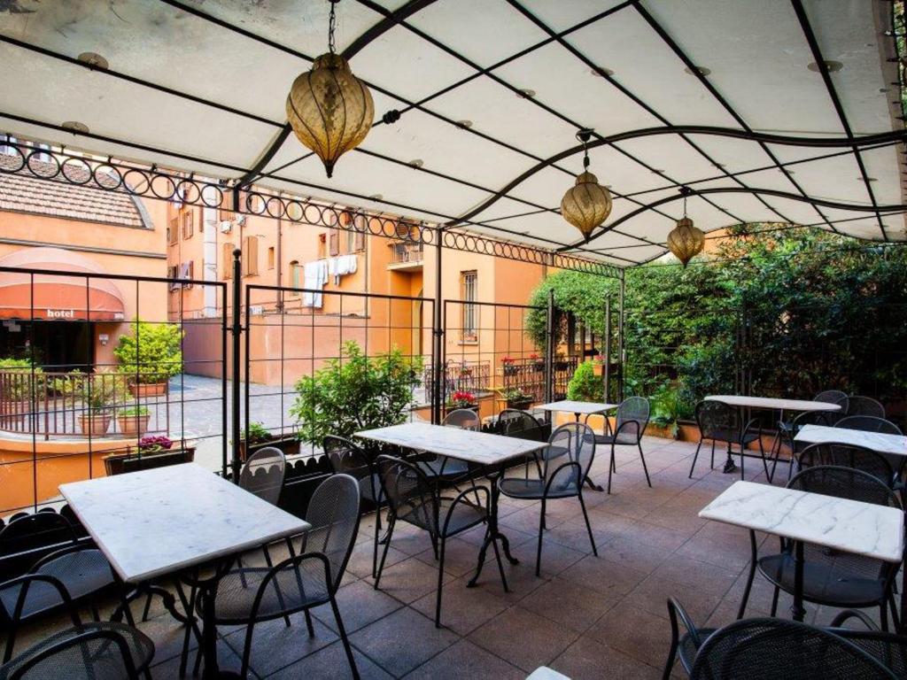
a patio area with tables, chairs and umbrellas at Hotel Astoria in Bologna
