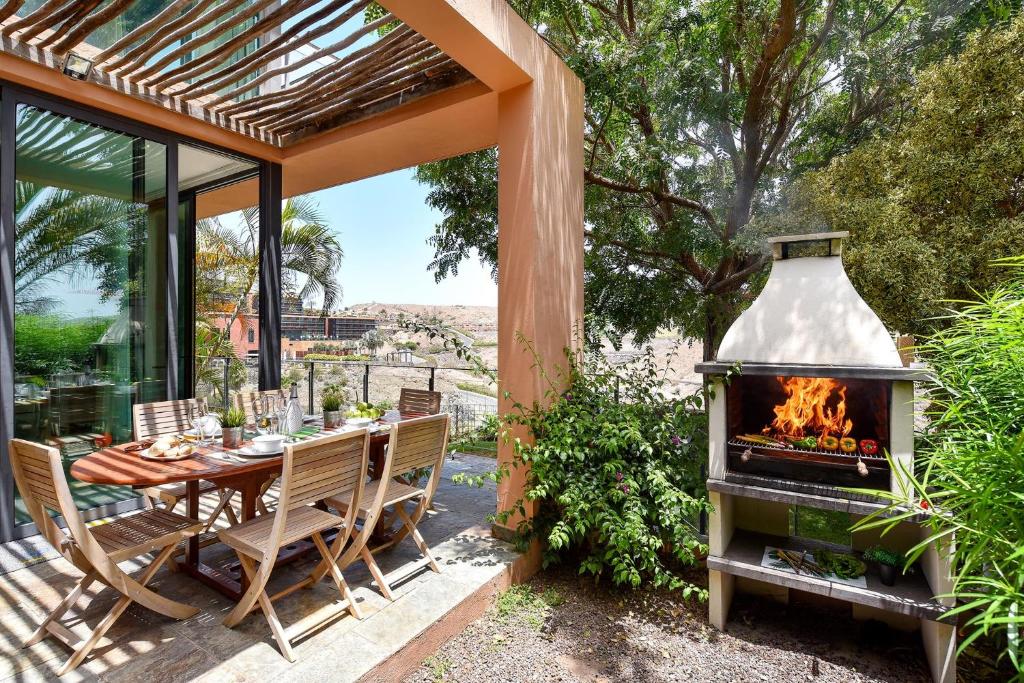un patio con mesa y chimenea en GreenSide 40 by VillaGranCanaria, en Maspalomas