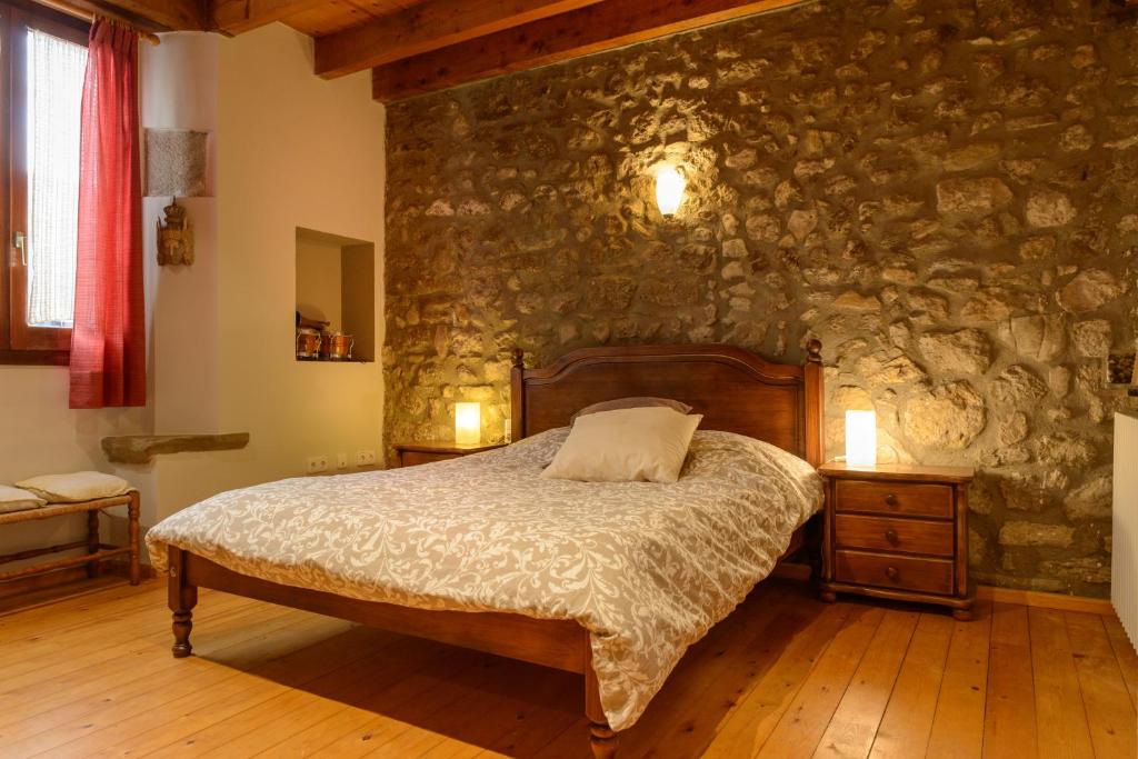 1 dormitorio con cama y pared de piedra en Habitación en casa rural en Bas