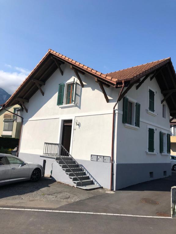 une maison blanche avec une voiture garée devant elle dans l'établissement Villa Matten, à Matten