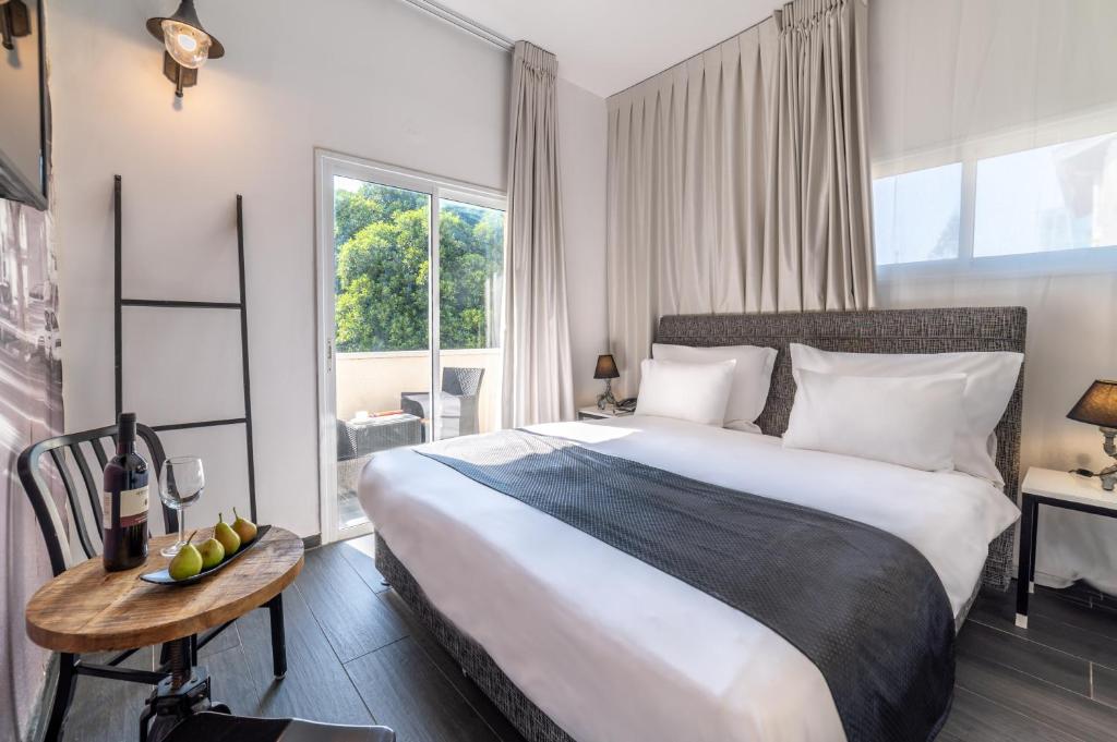 a bedroom with a large bed with a table and a window at Dizengoff Avenue Boutique Hotel in Tel Aviv