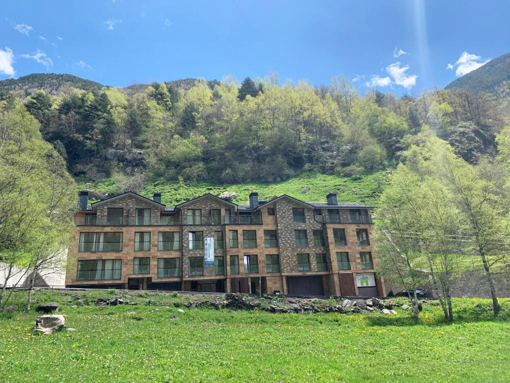 a large building with a green hill behind it at Apartamentos Llorts Ordino 3000 in Llorts