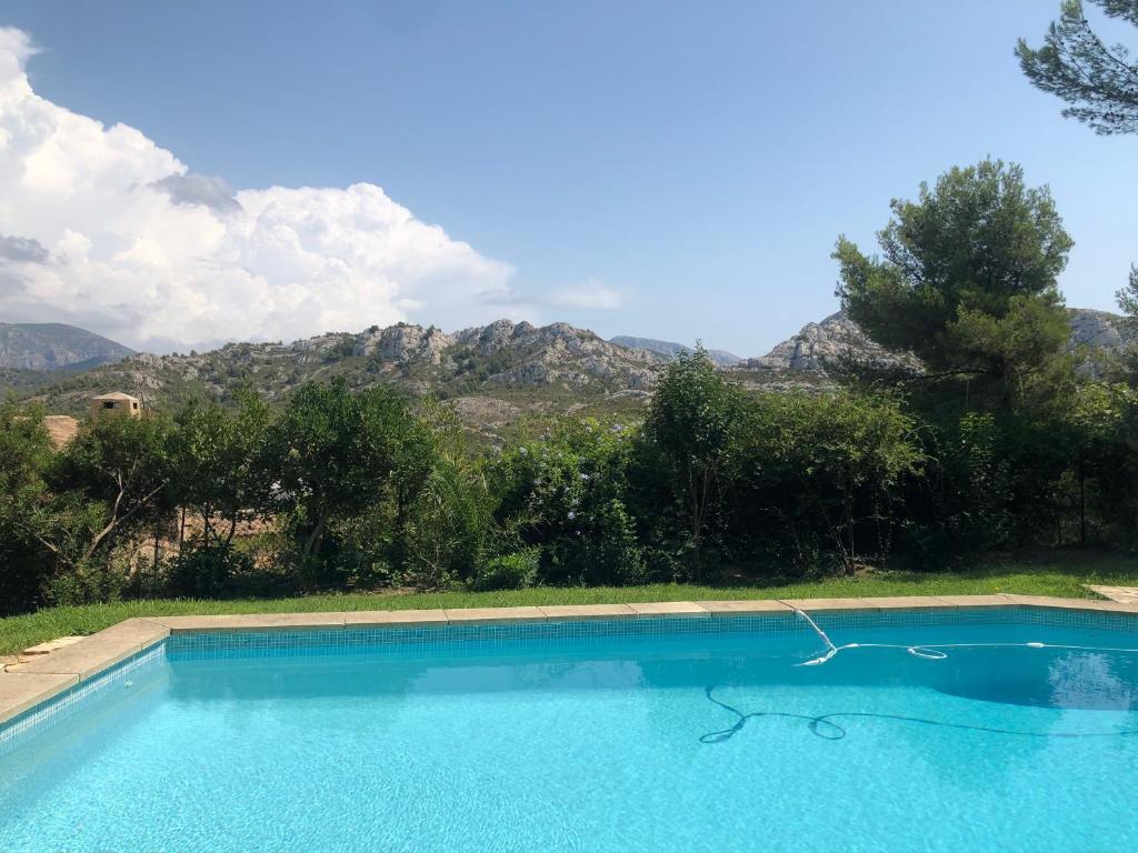a blue swimming pool with mountains in the background at L’appartement - Jardin Secret in Marseille
