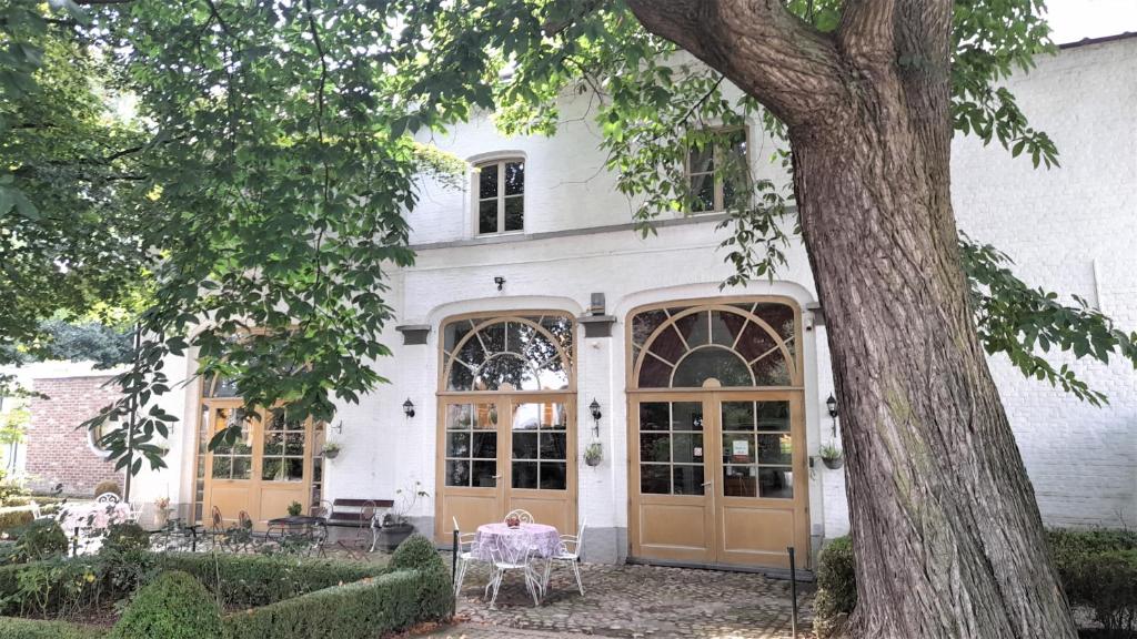 una casa bianca con porte marroni e un albero di Koetshuis Bosdam a Beveren