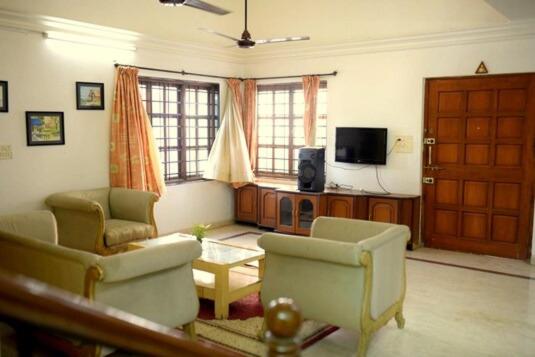 a living room with two chairs and a tv at Anna's Bungalow 4BHK in Alibaug
