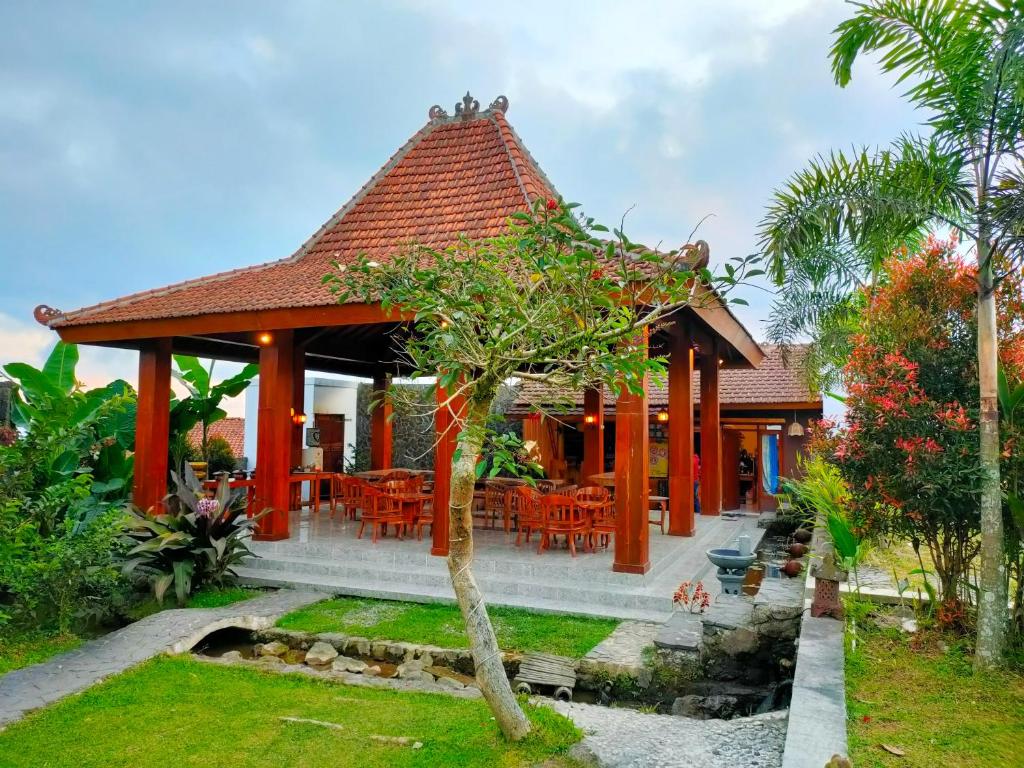 a pavilion with tables and chairs in a garden at Villa Sindoro Village in Wonosobo