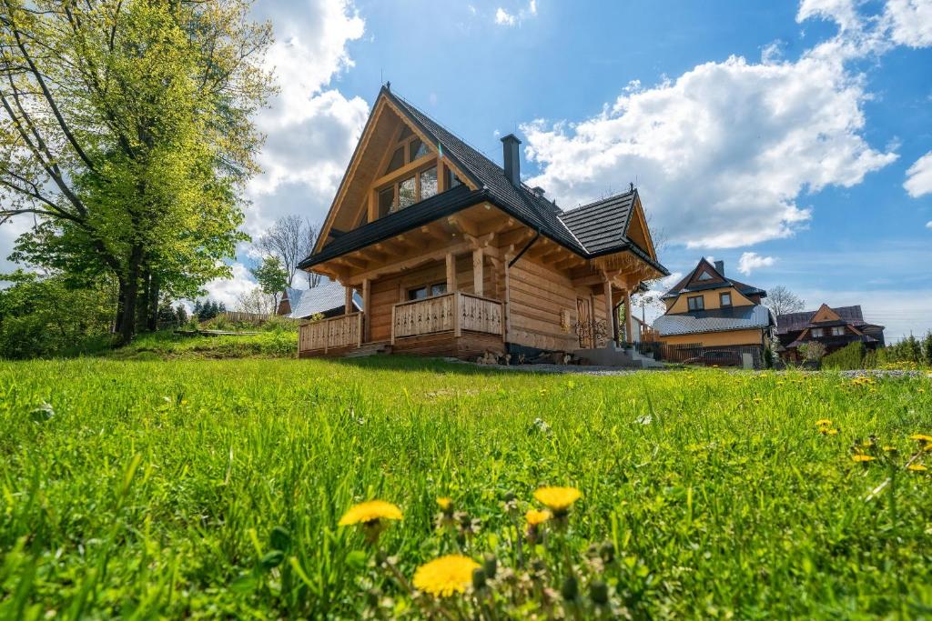 a log cabin in a field of green grass at Domek Góralski Modrzewiowa Weranda in Zakopane