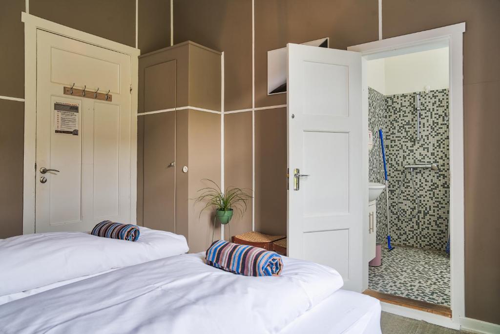 two white beds in a room with a shower at Hafaldan HI hostel, old hospital building in Seyðisfjörður
