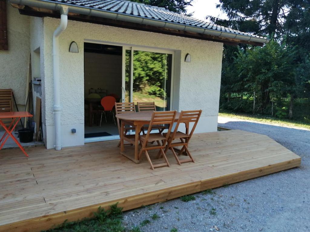 una terraza de madera con mesa y sillas. en Maison à la campagne en Lyaud