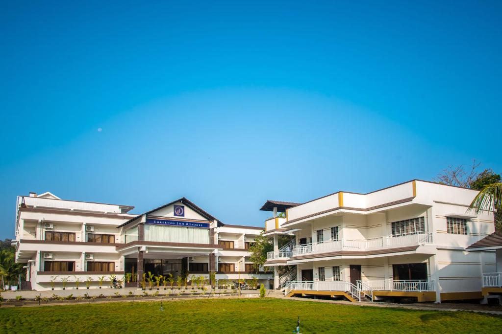 a row of white apartment buildings with a green lawn at Mastiff Select Shreeyog Resort in Dandeli