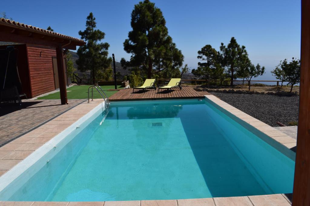 una piscina con 2 sillas y una casa en Finca La Baifa en Santa Cruz de Tenerife
