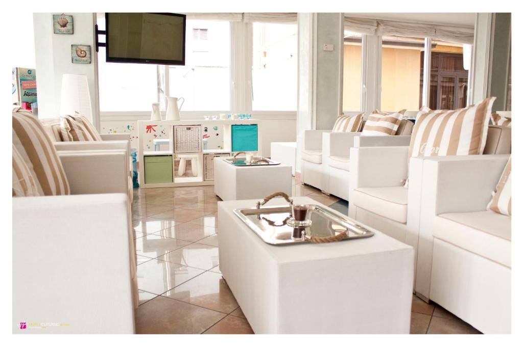 una stanza piena di sedie bianche e di una TV di Hotel Clitunno a Misano Adriatico