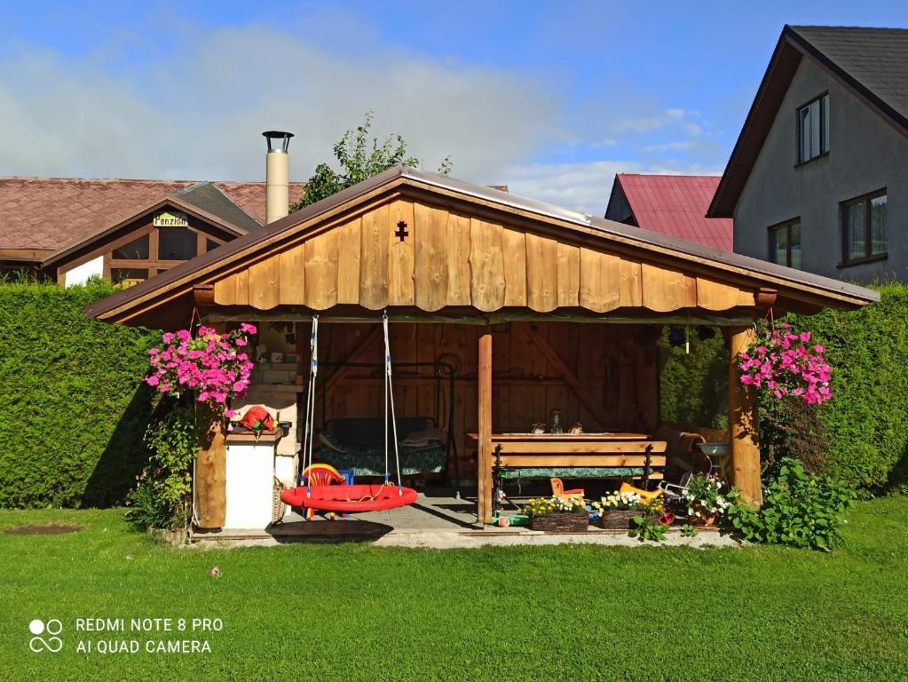 a wooden pavilion with a bench in a yard at Apartmány Grobarčík in Zuberec