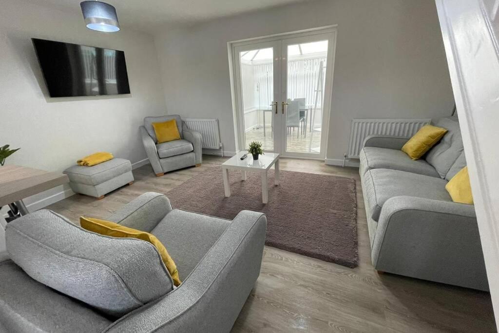 a living room with two couches and a table at Belmont Cottage in Billingham