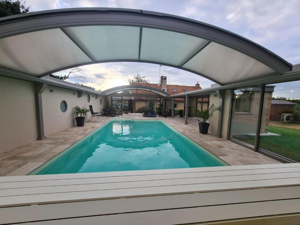 uma vista exterior de uma casa com uma piscina com um arco em Maison de vacances Daumeray em Daumeray