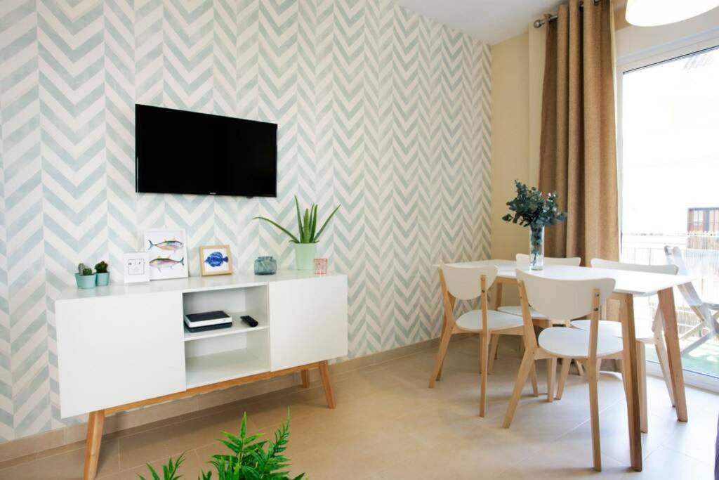 a living room with a table and a tv on a wall at Sweet Apartment in Málaga