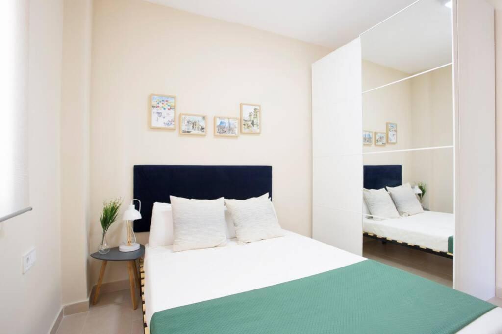 a white bedroom with a bed and a mirror at Sweet Apartment in Málaga