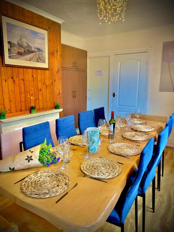 a long wooden table with blue chairs and plates on it at DEVON BEACH STATION in Paignton
