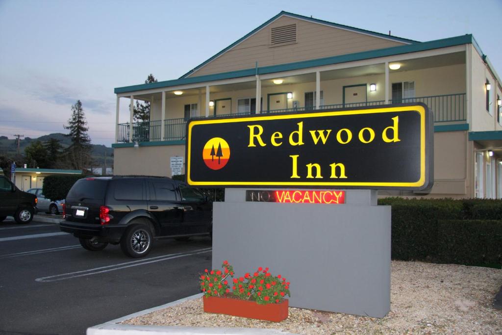 una señal para la posada de madera roja frente a un edificio en Redwood Inn, en Santa Rosa