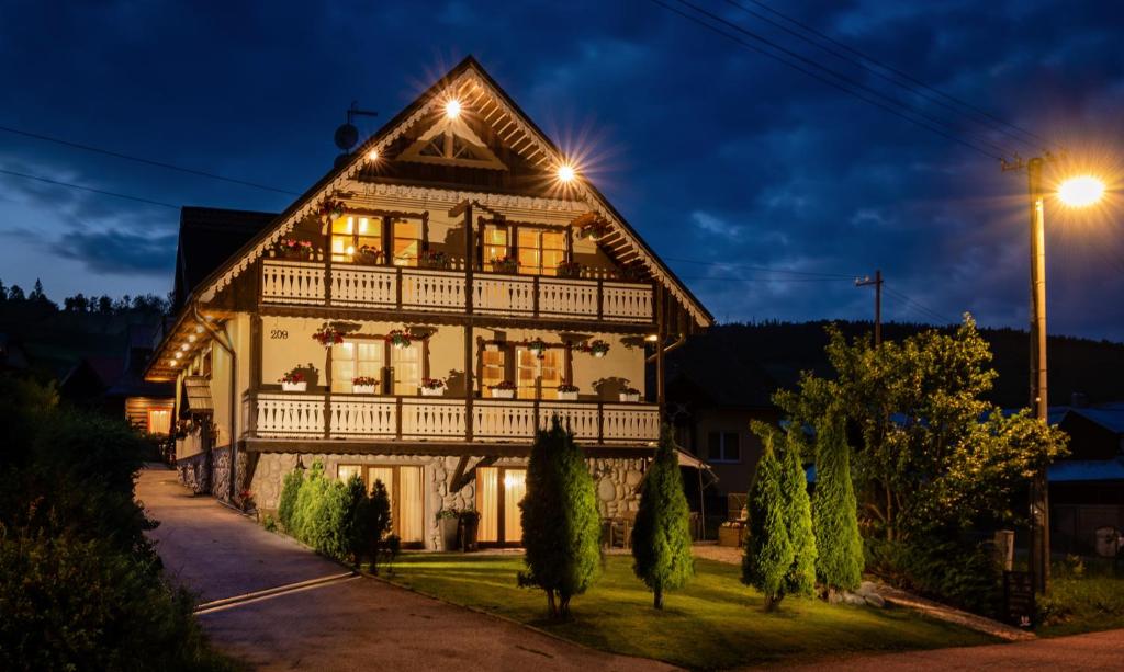 a large wooden house with lights on it at night at Penzion Enrico in Ždiar