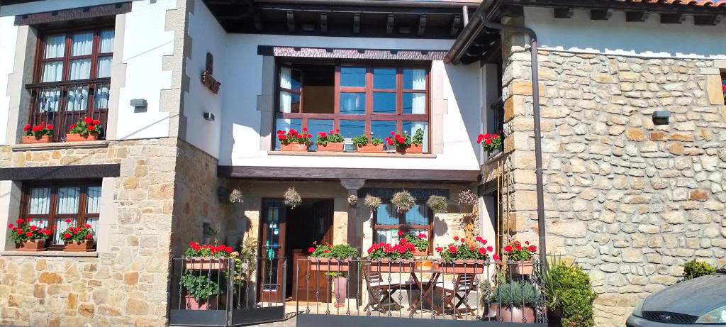 a house with red flowers in window boxes at Tiu Xico in Tereñes