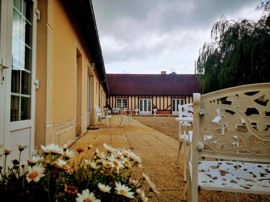 un patio con sillas y flores frente a un edificio en DSN - Domaine Suisse Normande, en Croisilles