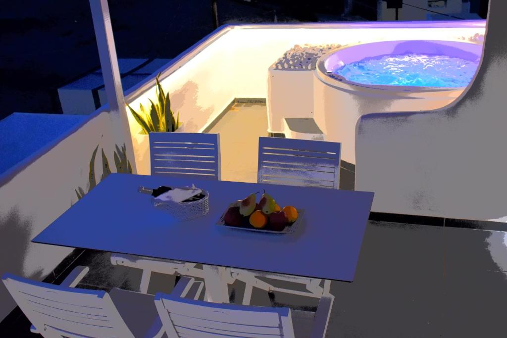 a table with a bowl of fruit next to a swimming pool at Ariana Eco Suites Adults Only in Fira