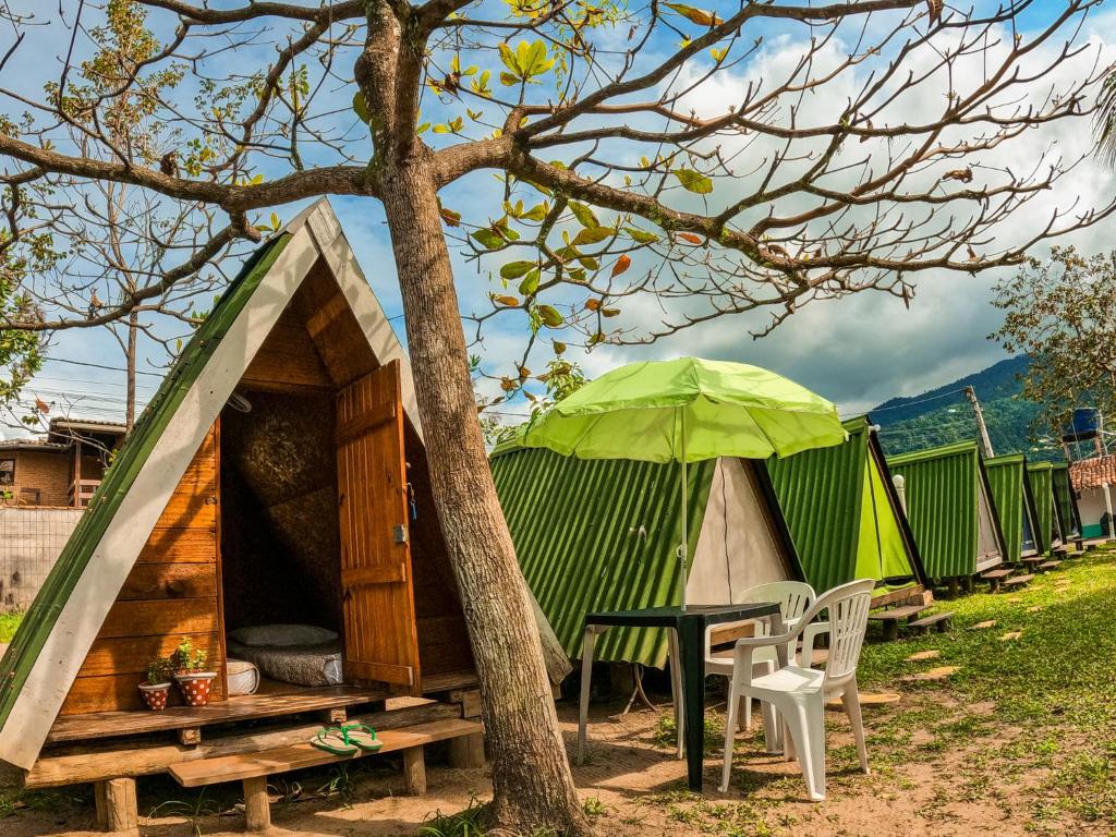 Tienda con mesa y sombrilla verde en Camping Marymar en Paraty