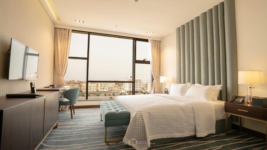 ジーザーンにあるIris Boutique Jazanのベッド、デスク、窓が備わるホテルルームです。