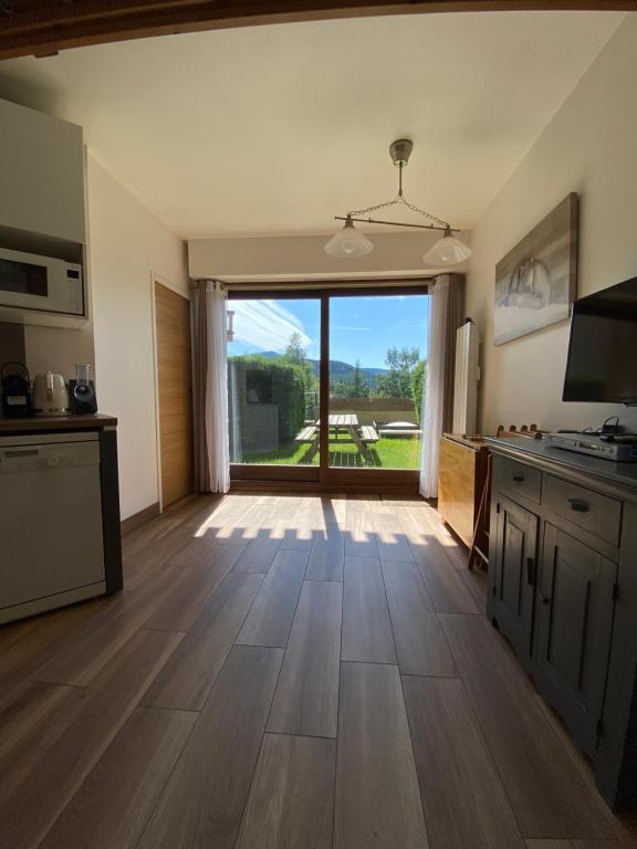 eine Küche mit Holzböden und einem großen Fenster in der Unterkunft Appartement avec rez de jardin, Sauna et Hamam in Villard-de-Lans