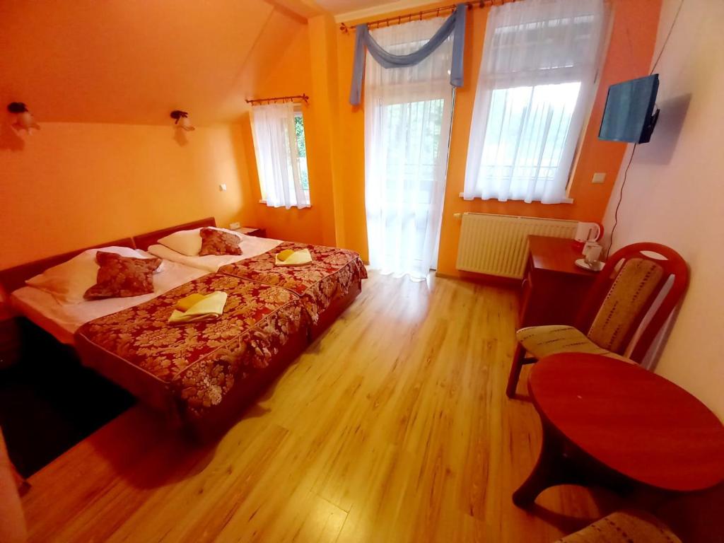 1 Schlafzimmer mit 2 Betten, einem Tisch und einem Fenster in der Unterkunft Willa Romantika in Kudowa-Zdrój