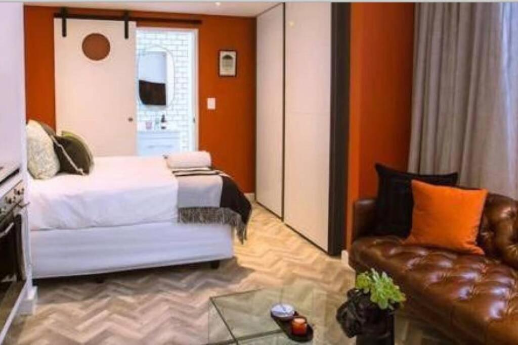 a bedroom with a bed and a leather couch at Luxurious Studio in the heart of Cape Town CBD in Cape Town